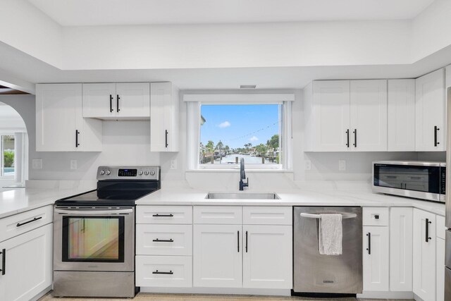 kitchen with appliances with stainless steel finishes, white cabinets, a wealth of natural light, and sink