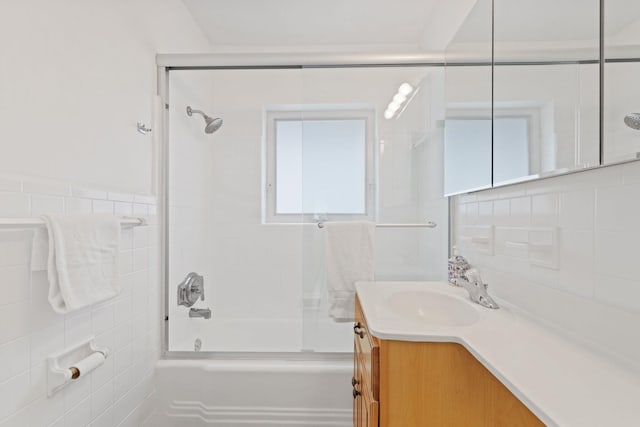 bathroom with tile walls, decorative backsplash, vanity, and shower / bath combination with glass door