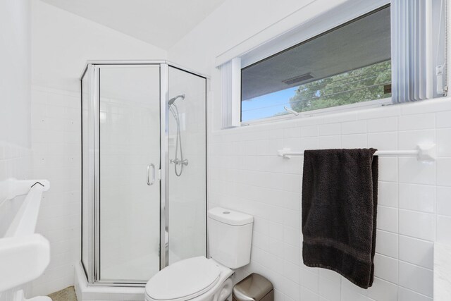 bathroom featuring tile walls, toilet, and walk in shower