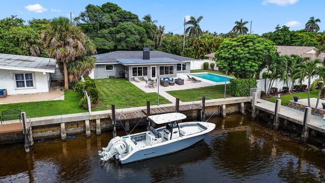 view of dock with a fenced in pool, a water view, a patio area, and a yard