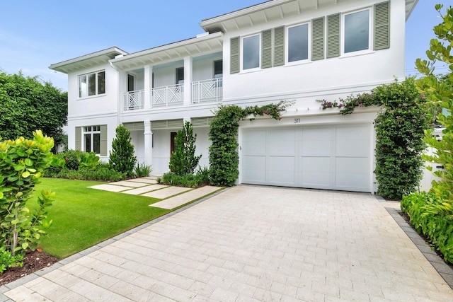 view of front of home featuring a garage, a balcony, and a front yard