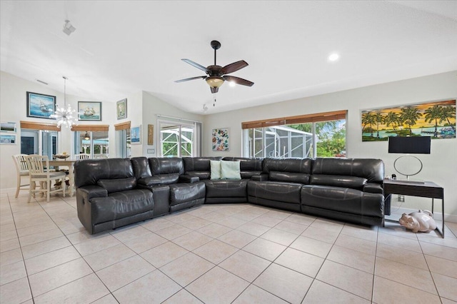 tiled living room with ceiling fan with notable chandelier, a wealth of natural light, and lofted ceiling