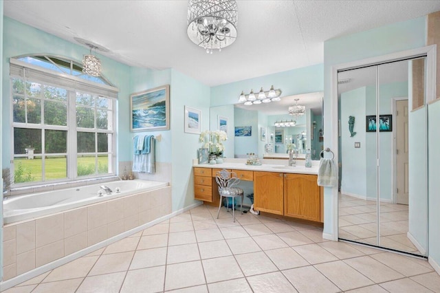 bathroom with tiled tub, tile patterned floors, an inviting chandelier, and vanity