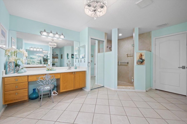 bathroom featuring tile patterned floors, an enclosed shower, an inviting chandelier, and vanity