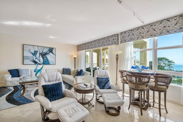 living room with light tile patterned flooring, french doors, a textured ceiling, and a water view