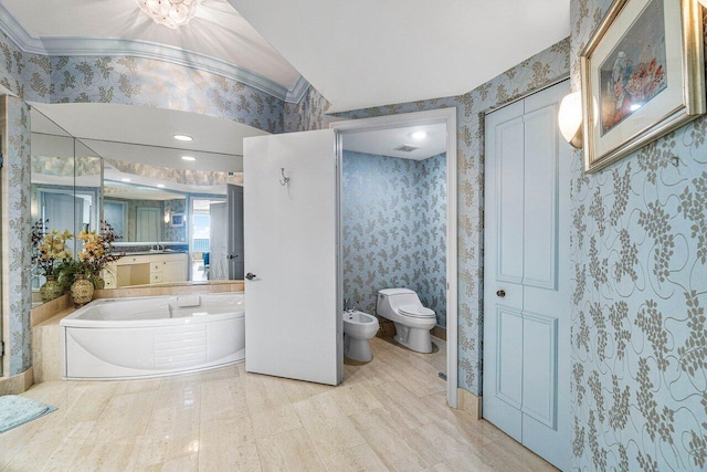 bathroom with toilet, a bidet, vanity, crown molding, and a bathing tub