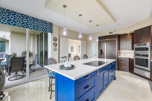 kitchen featuring black electric cooktop, stainless steel double oven, a center island, paneled refrigerator, and hanging light fixtures