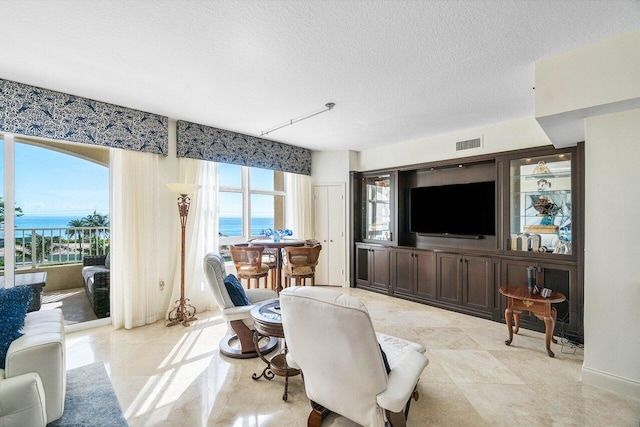 tiled living room with a textured ceiling and plenty of natural light