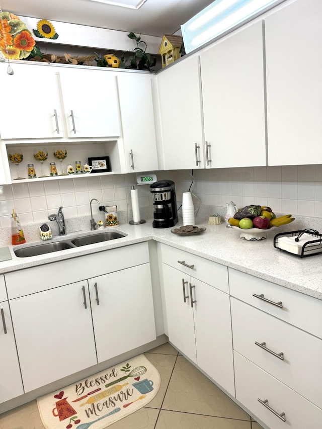 kitchen with white cabinets, light tile patterned flooring, sink, and backsplash