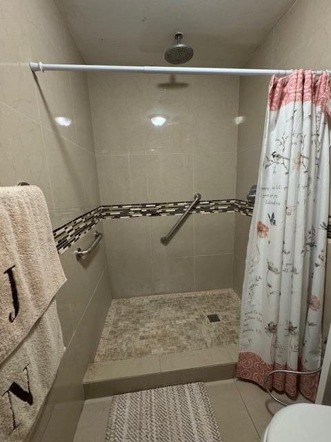 bathroom featuring a shower with curtain, tile patterned flooring, and toilet