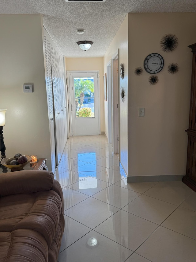 hall featuring light tile patterned floors and a textured ceiling