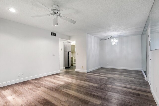 spare room with a textured ceiling, ceiling fan with notable chandelier, and wood-type flooring