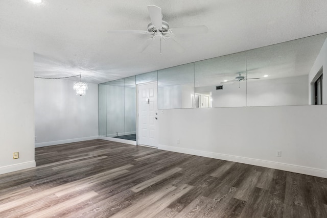 basement featuring ceiling fan with notable chandelier, dark hardwood / wood-style flooring, and a textured ceiling