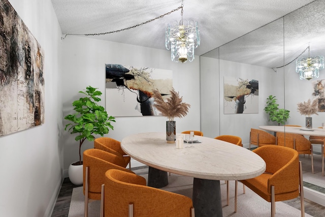 dining room with baseboards, a textured ceiling, an inviting chandelier, and wood finished floors