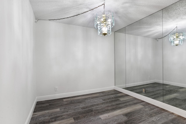 empty room featuring dark hardwood / wood-style floors, an inviting chandelier, and a textured ceiling