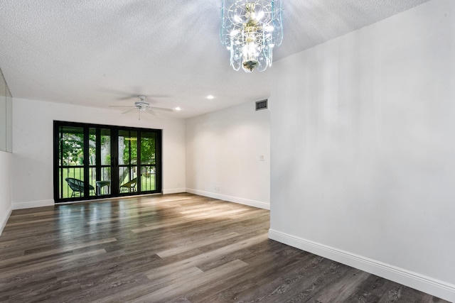 empty room featuring a textured ceiling, dark wood-type flooring, and ceiling fan with notable chandelier