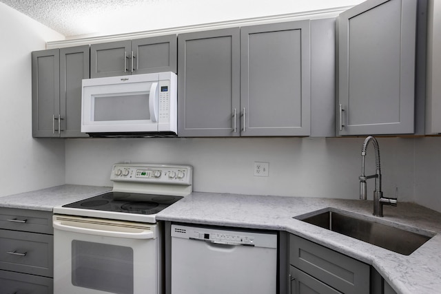 kitchen featuring gray cabinets, white appliances, a textured ceiling, and sink