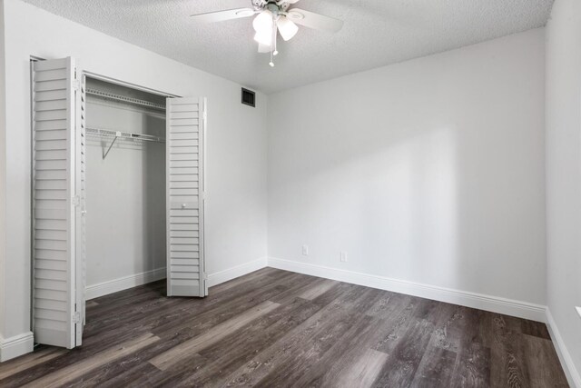 unfurnished bedroom with a closet, a textured ceiling, ceiling fan, and dark hardwood / wood-style floors