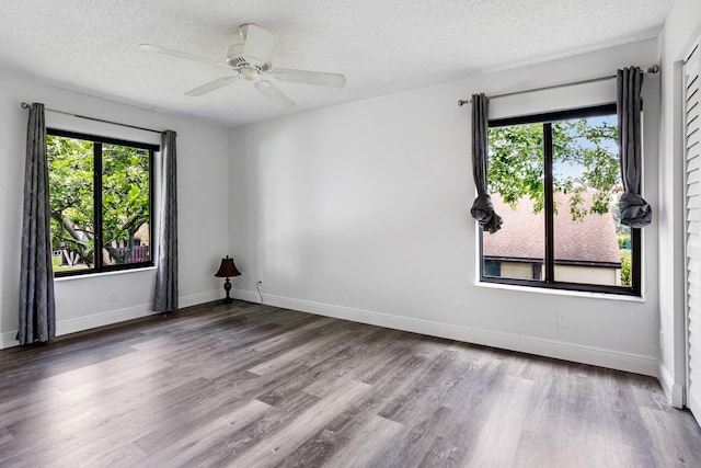 unfurnished room with a textured ceiling, a healthy amount of sunlight, ceiling fan, and wood-type flooring