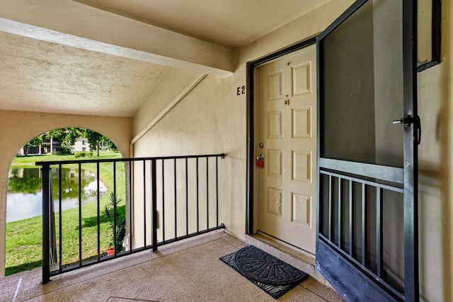 view of exterior entry featuring a water view and a balcony