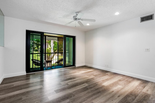 empty room featuring a textured ceiling, wood finished floors, visible vents, and baseboards