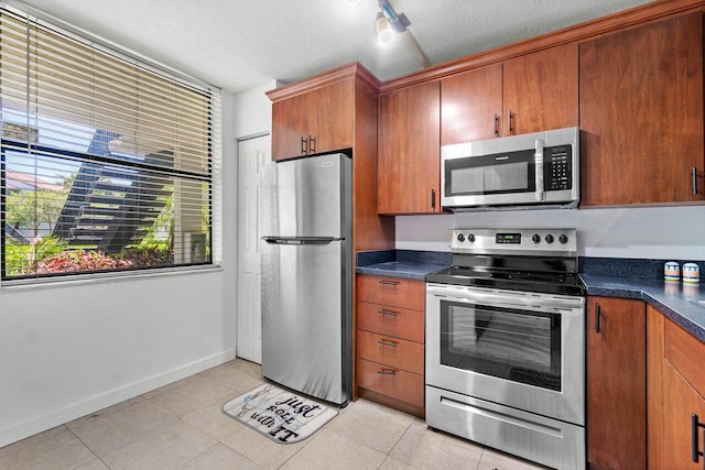 kitchen featuring light tile patterned flooring, stainless steel appliances, and a textured ceiling