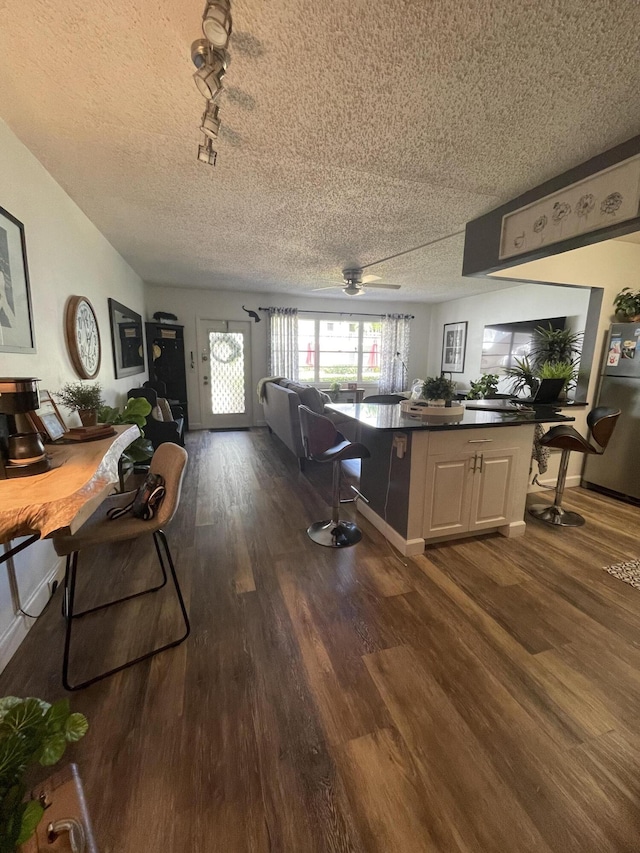 kitchen with a textured ceiling, white cabinets, ceiling fan, hardwood / wood-style flooring, and stainless steel refrigerator