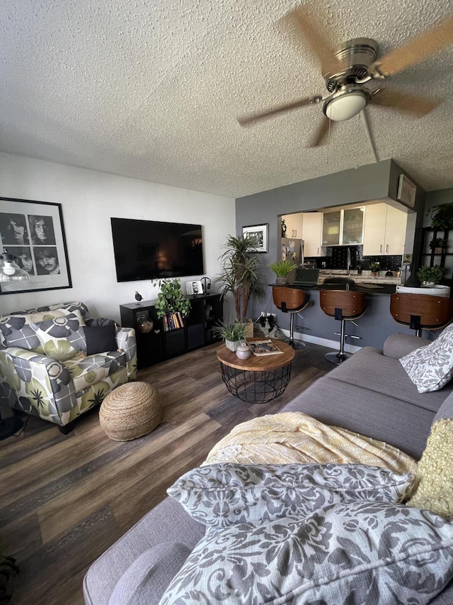 living room with ceiling fan, dark wood-type flooring, and a textured ceiling