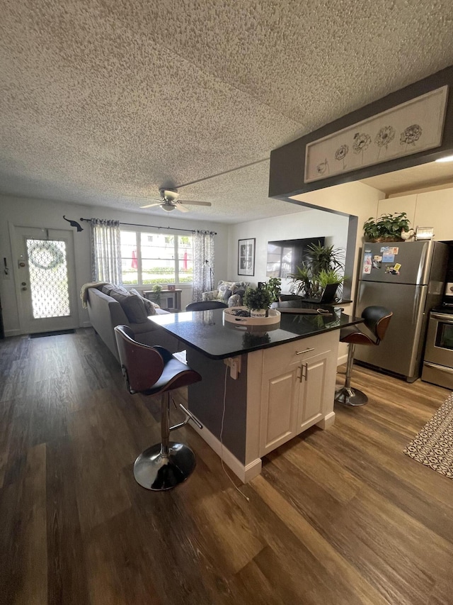 kitchen featuring ceiling fan, white cabinets, stainless steel refrigerator, and wood-type flooring