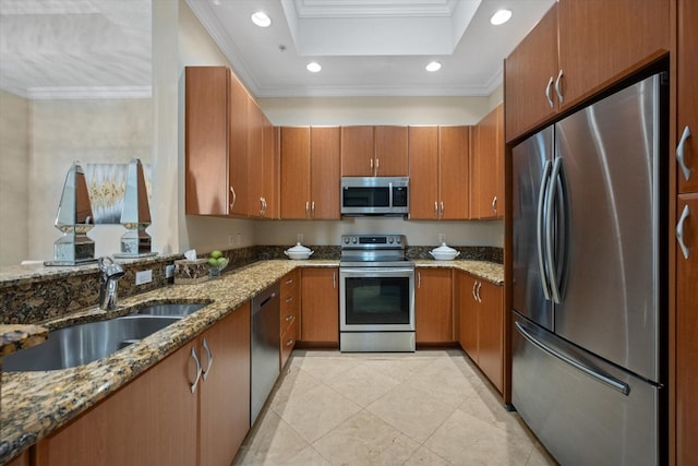 kitchen featuring appliances with stainless steel finishes, a tray ceiling, crown molding, and dark stone countertops