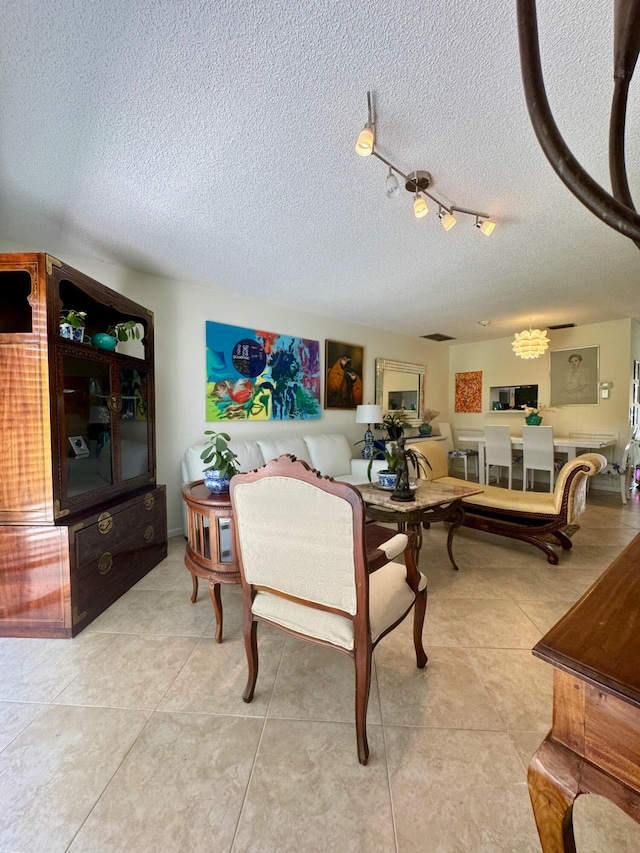 living room with a textured ceiling, rail lighting, and light tile patterned floors