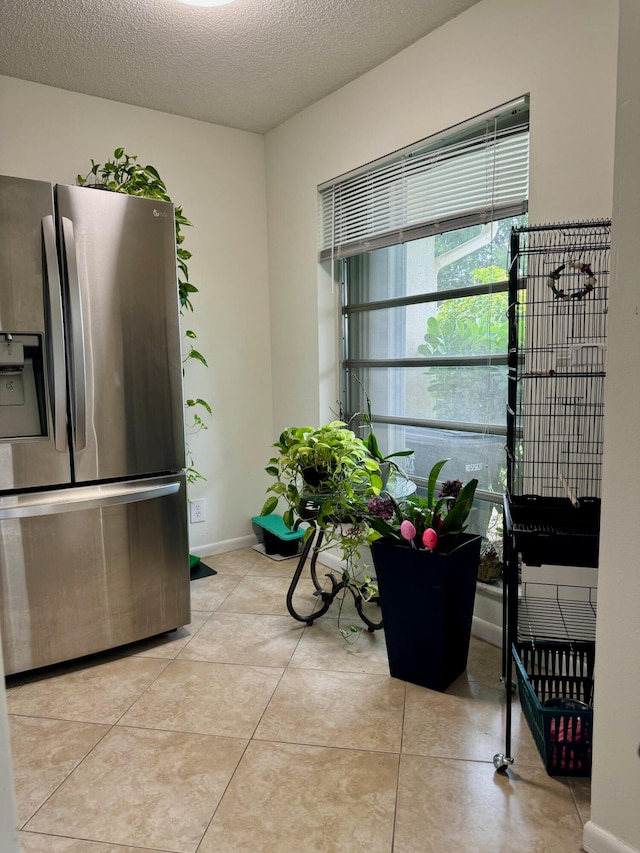 kitchen featuring a textured ceiling, light tile patterned floors, and stainless steel refrigerator with ice dispenser