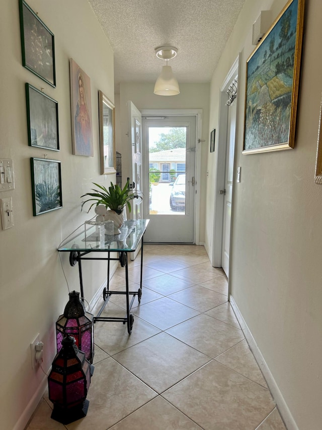 doorway to outside with a textured ceiling and light tile patterned flooring