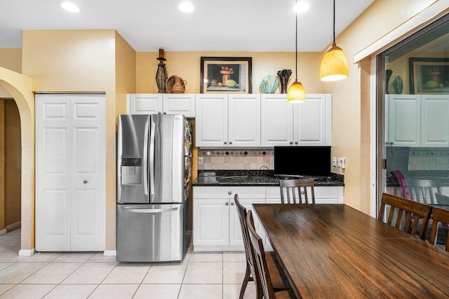 kitchen with stainless steel fridge with ice dispenser, pendant lighting, white cabinets, and tasteful backsplash