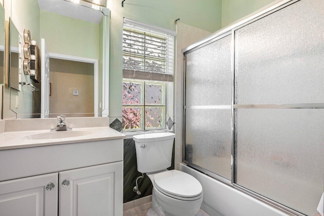 full bathroom featuring vanity, bath / shower combo with glass door, and toilet