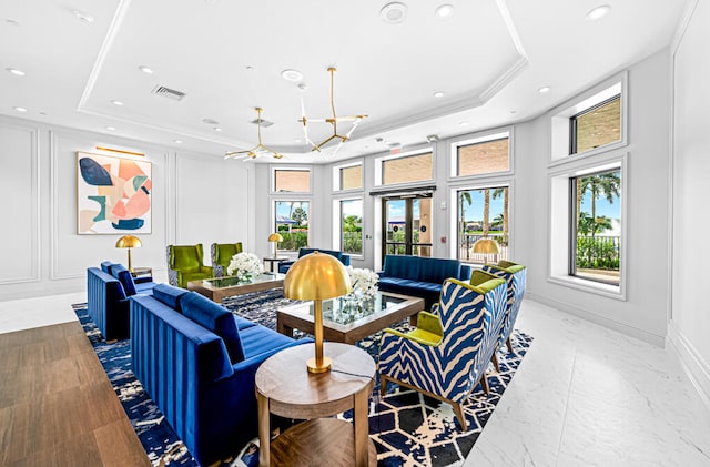 living room featuring crown molding, a notable chandelier, a healthy amount of sunlight, and a raised ceiling