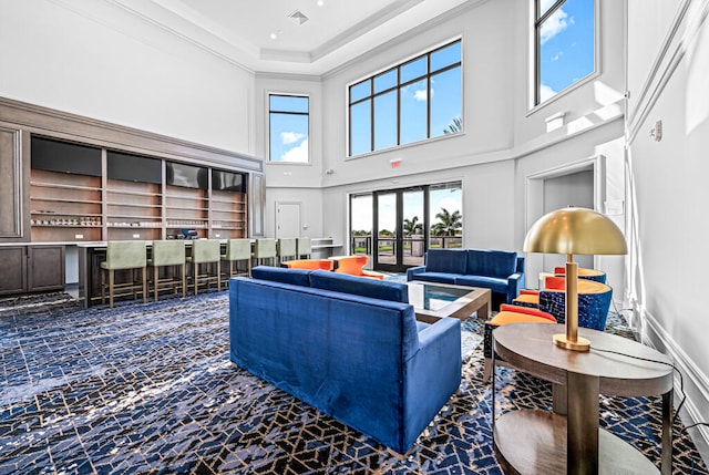 carpeted living room featuring a towering ceiling and crown molding