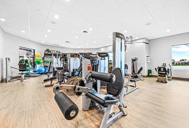 gym with light hardwood / wood-style floors and a paneled ceiling