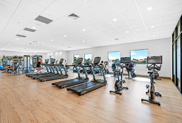 workout area with light hardwood / wood-style floors and a paneled ceiling