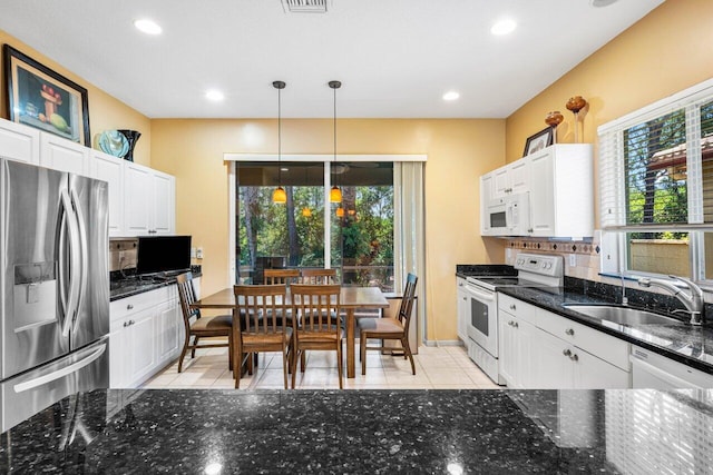 kitchen with white appliances, white cabinets, a wealth of natural light, and hanging light fixtures