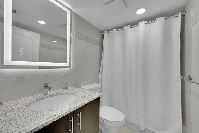 bathroom featuring vanity, tile walls, and toilet