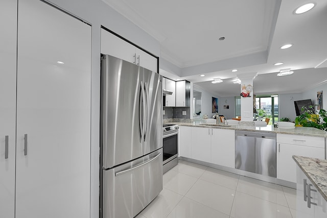 kitchen with crown molding, appliances with stainless steel finishes, light stone countertops, light tile patterned floors, and white cabinets