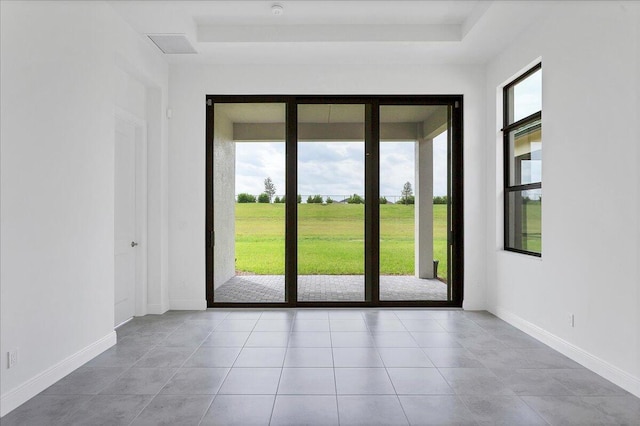 entryway featuring a raised ceiling and light tile patterned floors