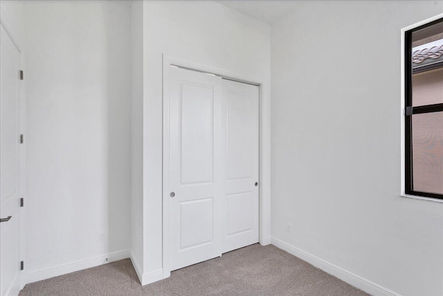 unfurnished bedroom featuring light colored carpet and a closet