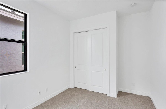 unfurnished bedroom featuring light colored carpet and a closet