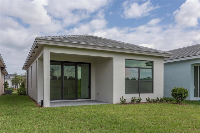 rear view of property with central AC unit and a yard