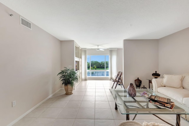 living room featuring ceiling fan, light tile patterned floors, and a textured ceiling