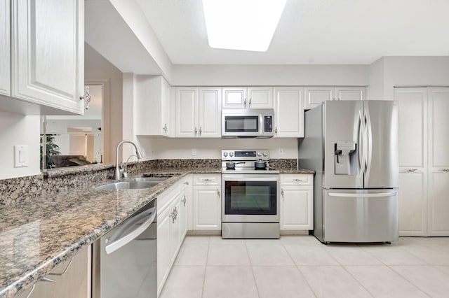 kitchen with white cabinets, appliances with stainless steel finishes, dark stone countertops, and sink