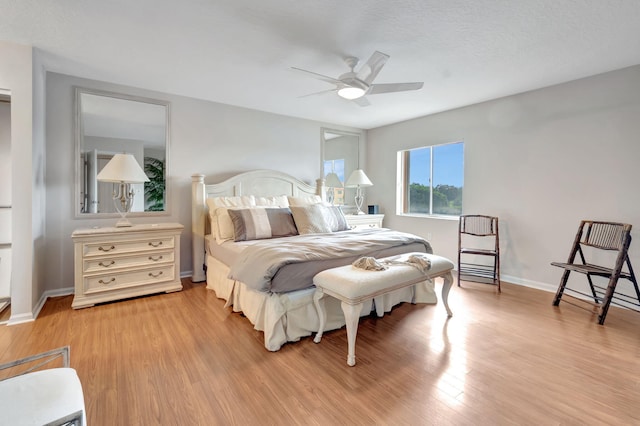 bedroom with light wood-type flooring, ceiling fan, and a textured ceiling