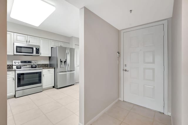 kitchen featuring stainless steel appliances, light tile patterned floors, and white cabinetry